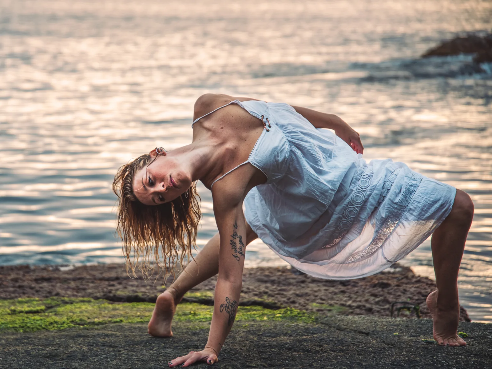 Carola Gatti in una posizione yoga sugli scogli al tramonto