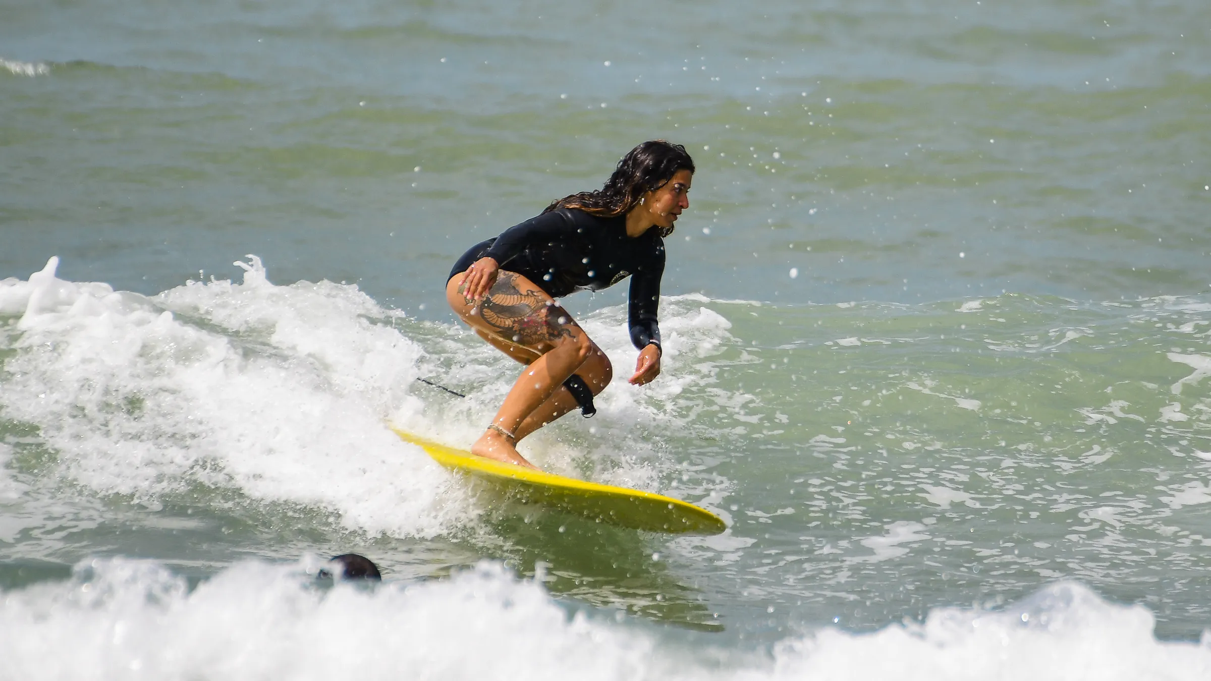 Una surfista cavalca un'onda sulla sua tavola gialla