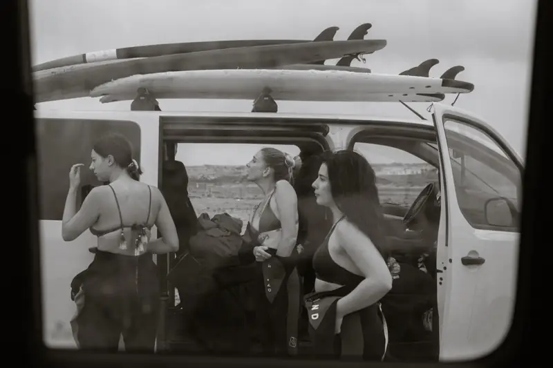 Surfiste accanto a un furgone con le tavole sul tetto
