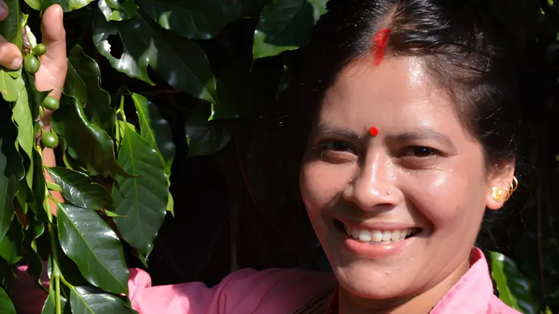 Una donna nepalese sorridente tra le piante