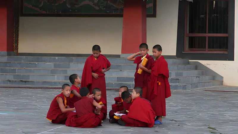Giovani monaci buddhisti in tunica rossa nel cortile di un monastero