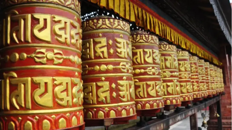Ruote della preghiera dorate e rosse in un tempio buddhista