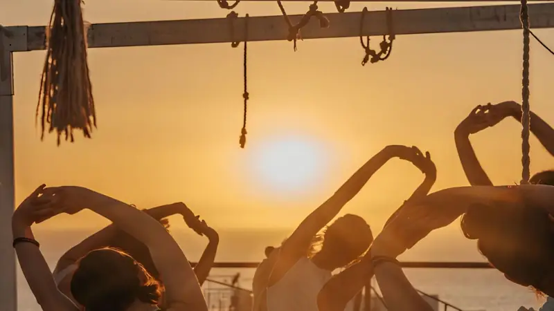 Un gruppo pratica yoga al tramonto sulla terrazza di un lodge sull'oceano